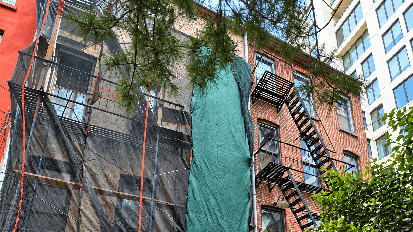 Protected construction façade with scaffold and fire escape during demolition preparation
