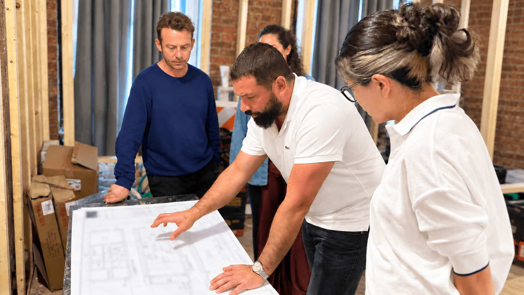 Alexander Home Collection reviewing construction plans with clients inside a framed renovation