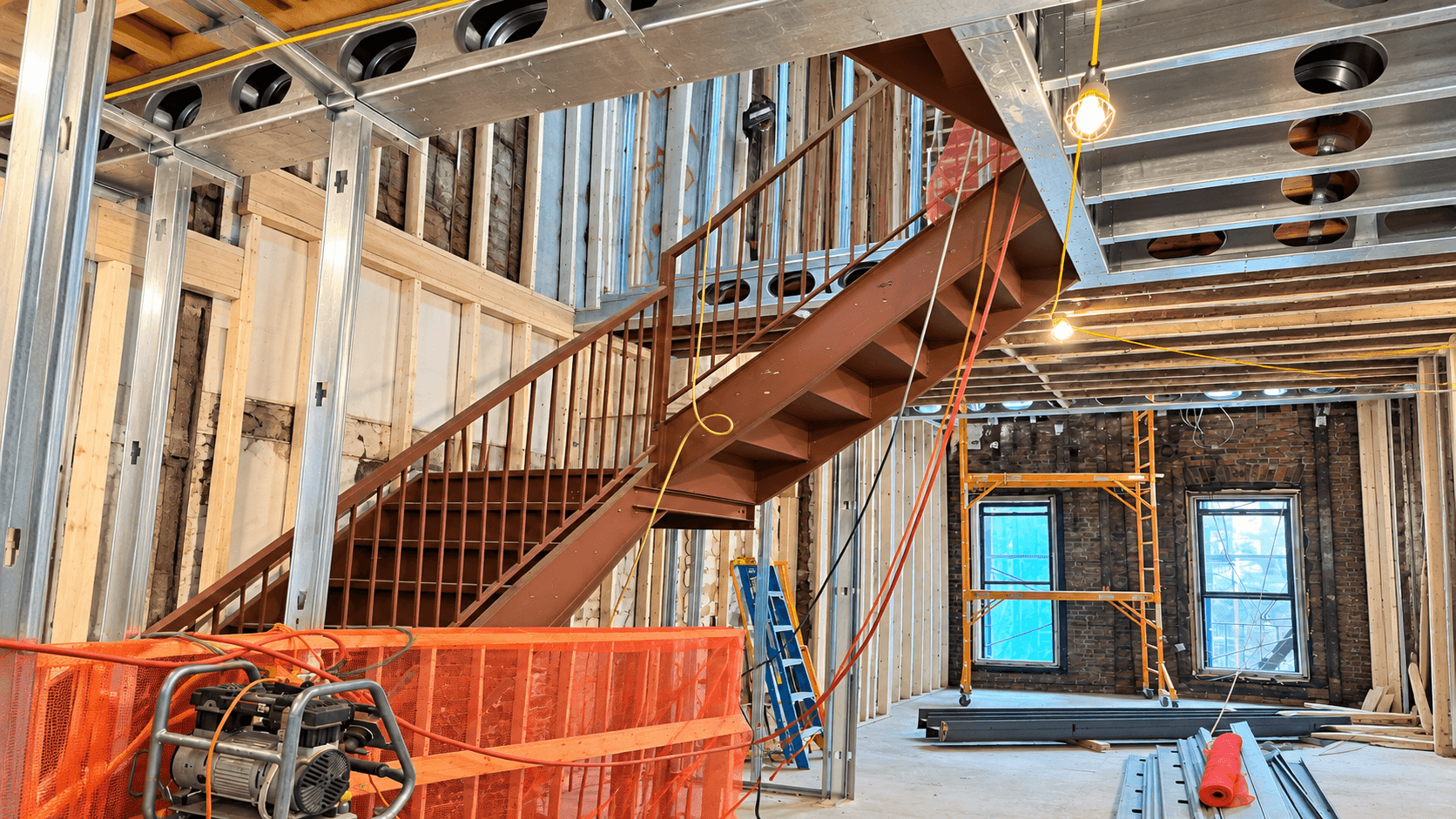Exposed ductwork, steel framing, wiring, and stair structure during rough-in