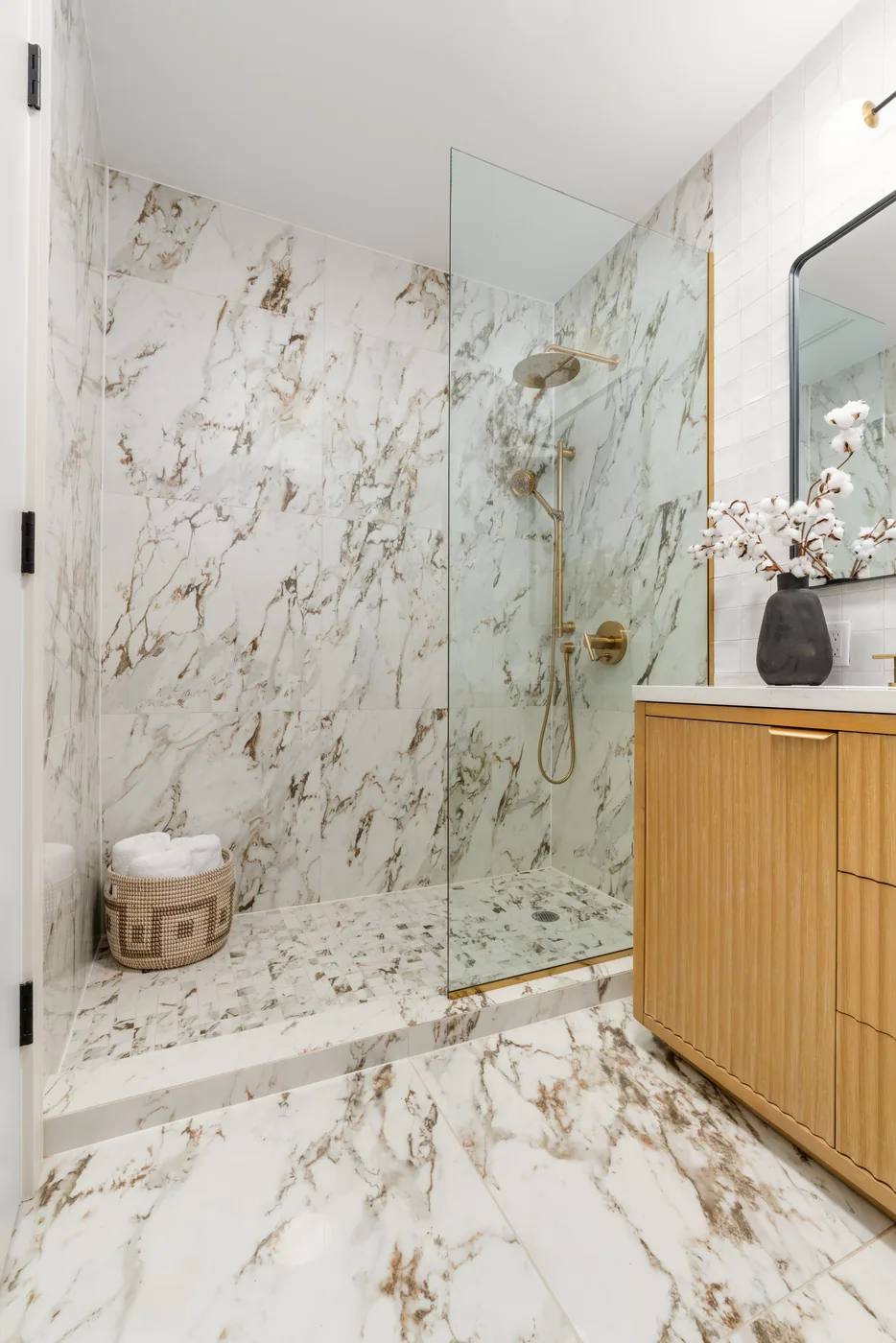 Marble walk-in shower with wood vanity